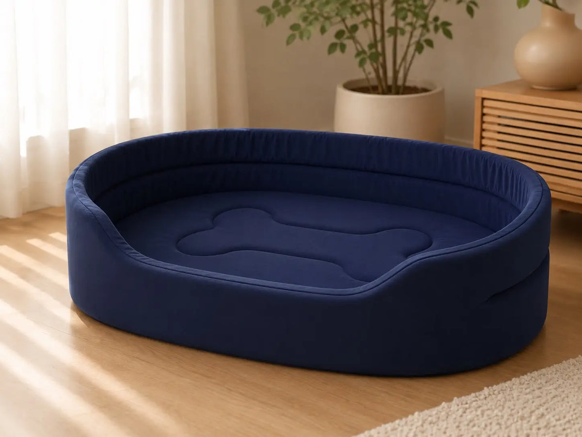 Navy blue Cozy Pet Mattress Bed with soft raised cushioned sides, plush padded sleeping surface and bone-shaped center detail, placed on a wooden floor in a bright modern living room for dogs and cats.